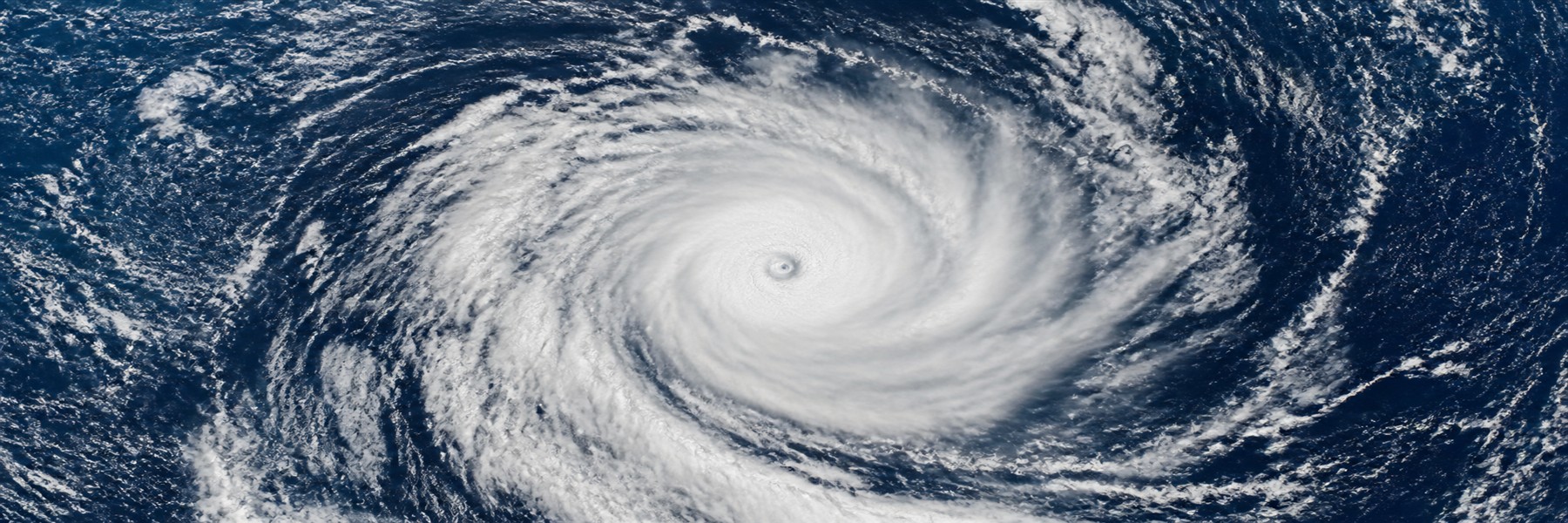 濃い青の海上で大きな渦を巻く台風の雲を上空から見た衛星画像風の情景