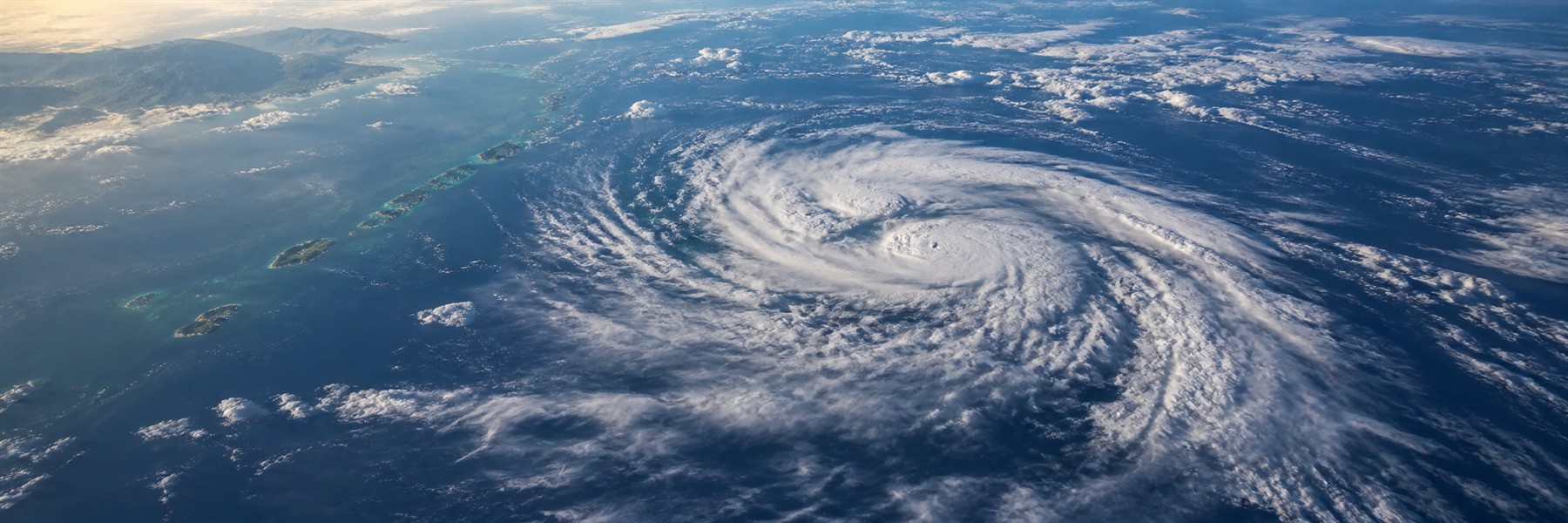 沖縄の島々の南側の海上に広がる台風の渦状の雲を高高度から見た様子